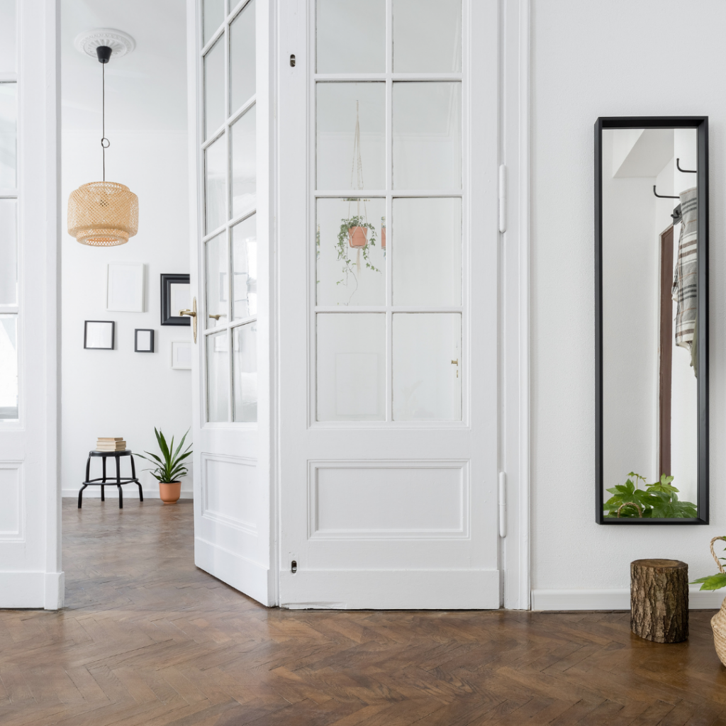 entry way with white door, a mirror, and a peg rack
